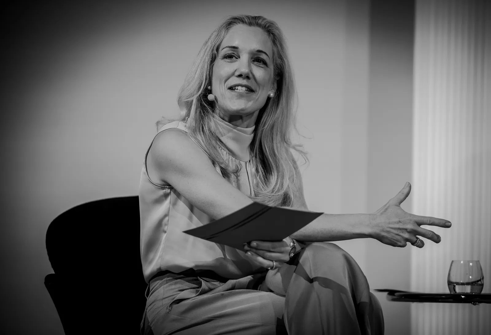 Isabel Schürmann sitzt auf einer Bühne und erläutert gestikulierend einen Gedanken